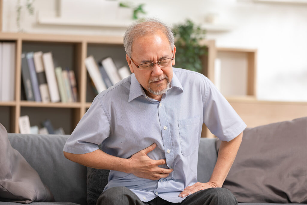senior men holding his stomach feeling pain while sitting sofa home asian man having stomachache with isolated gastric senior suffering from digestion problem acid reflux
